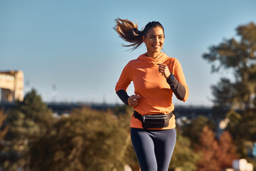 Young happy female athlete jogging in nature.
