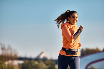 Happy sportswoman running during her daily workout routine.