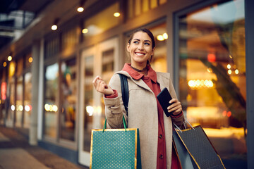 Young woman carrying shopping bags and feeling satisfied after spending day at mall.