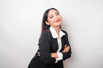 Portrait of a confident smiling Asian girl boss wearing black suit standing with arms folded and looking at the camera isolated over white background