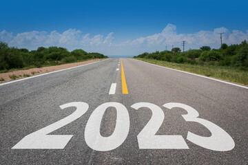Año nuevo 2023 o concepto de inicio.. Palabra 2023 escrita en la carretera asfaltada en día radiante. Concepto de desafío y cambio. - obrazy, fototapety, plakaty