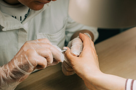 Manicurist cutting cuticle with nail pliers