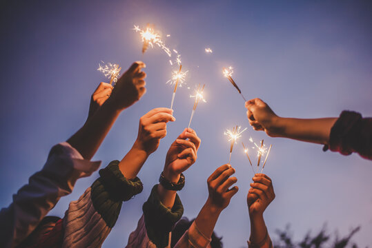 Group of young friends enjoy with burning sparkler in hands together