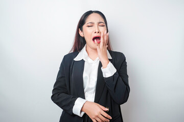 Fototapeta na wymiar Portrait of sleepy attractive Asian woman wearing a black suit, feeling tired after overtime at work, yawning, covering opened mouth with palm
