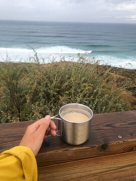 ugc of a woman holding a cup of coffee in front of the sea