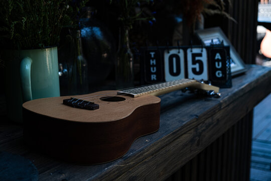 The ukulele lies on wood table. Calender on background.