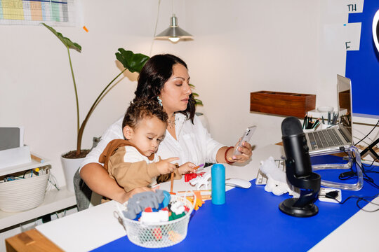 Mom working while her toddler plays at desk