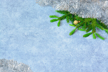Light gray background with fir branch, garland and small gold Christmas ball