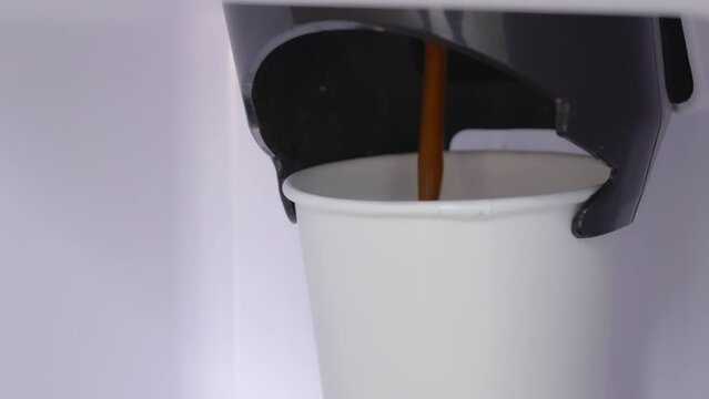 Automatic coffee machine with hot coffee white paper cup, Vending coffee machine pouring in a paper glass in morning drink, Close up slow motion and handhelds.