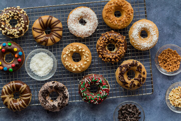 Assorted homemade donuts with various glazes and toppings, on a cooling rack.