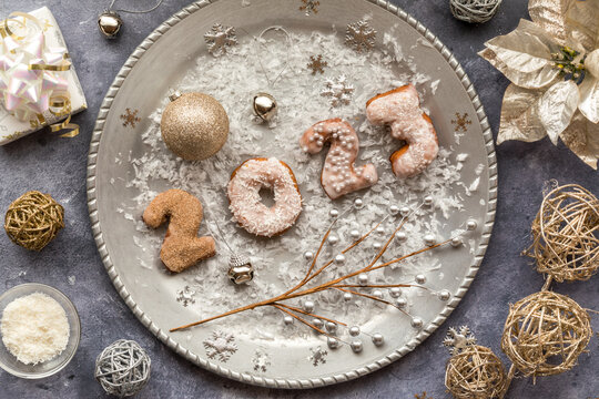 A silver platter with 2023 sprinkled donuts surrounded by festive decorations.