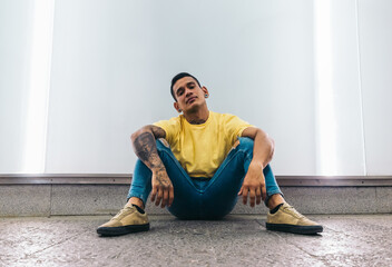 Tattooed expressive latin man sitting on the floor