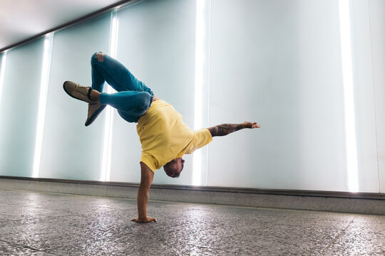 Young man doing one handed handstand and breakdancing