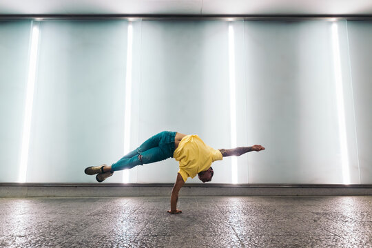 Young man doing one handed handstand and breakdancing