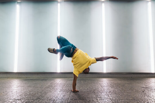 Young man doing one handed handstand and breakdancing
