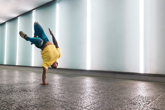 Young man doing one handed handstand and breakdancing