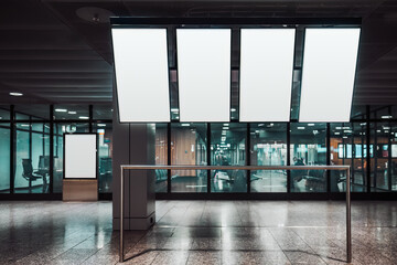 Four vertically oriented blank mock-ups of tv screens of a departure and arrival board, and a template of an indoor ad billboard aloof near a glass wall of an airport or a train station waiting hall - obrazy, fototapety, plakaty