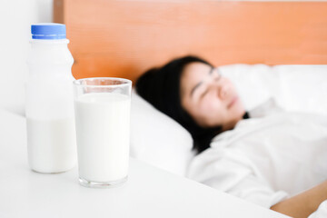 Obraz na płótnie Canvas Asian woman drinking milk before sleeping in bed