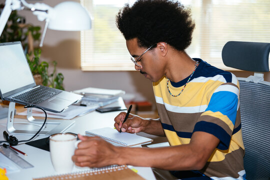 Male Freelancer Making Notes In Planner