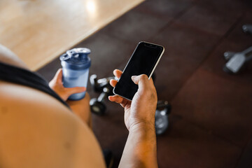 Asian man using phone in gym