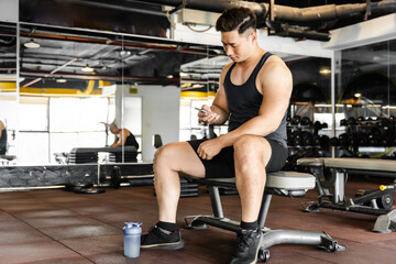 Asian man using phone in gym