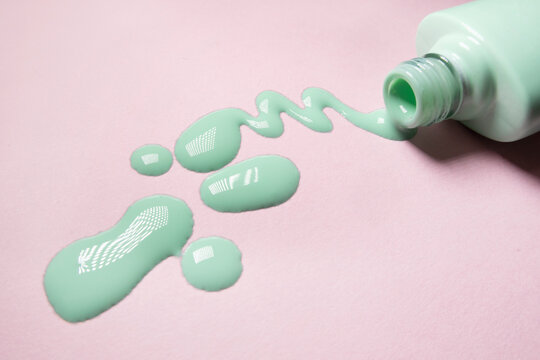 pastel green nail polish spill on pink background
