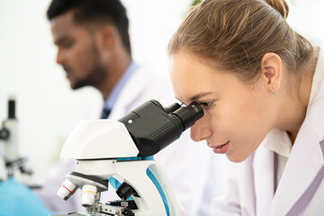 Obraz na płótnie Canvas Group of Microbiologist Looking at a Lab-Grown Cultured Vegan Meat Sample in a Microscope. Medical Scientist Working on Plant-Based. medical biotechnology research laboratory using microscope.