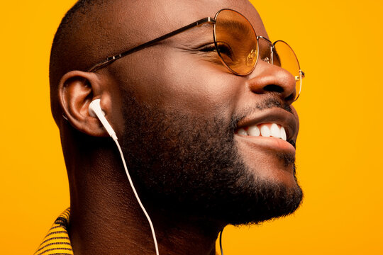 Cheerful black man in eyeglasses and earphones