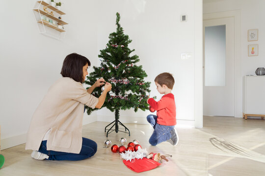 Family decorating a small christmas tree at home
