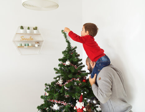 Father helping his son to decorate the Christmas tree