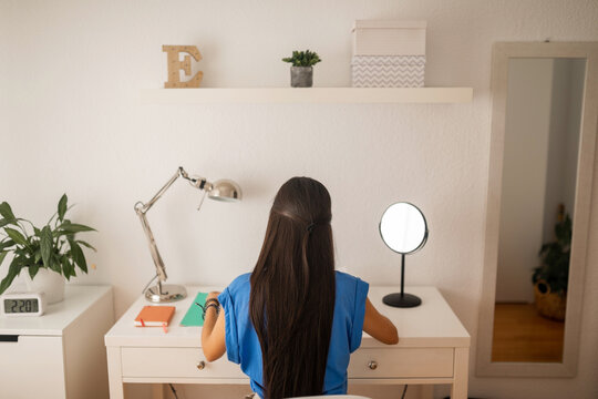 teenage girl studying at her bedroom desk