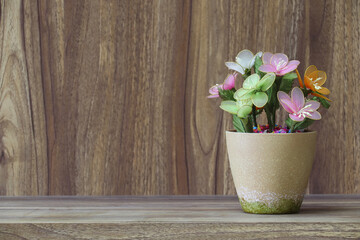 Fake flowers in a vase placed on a table on a wooden table with copy space for design wood grain vintage background.