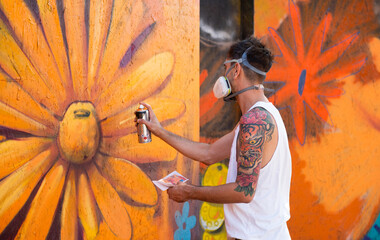 Graffiti artist painting large floral mural