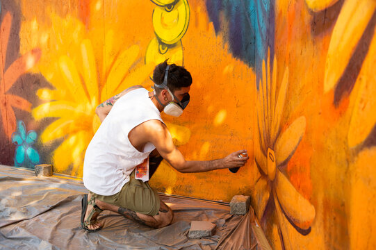 Graffiti artist painting large floral mural