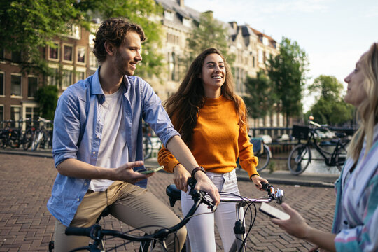 Group of friends riding bikes and using smartphone in Amsterdam