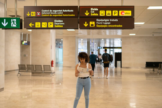 Black woman reading map under direction signs