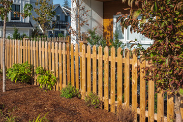 Nice wooden fence around house. Wooden fence with green lawn. Street photo