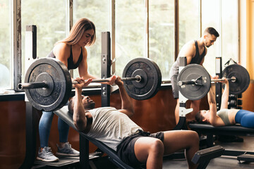 People training bench press in the gym with spotters