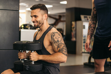 Man training dumbbell bench press in gym with spotter