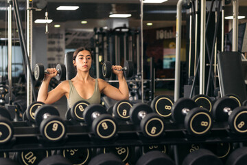 Strong woman training with dumbbells in the gym