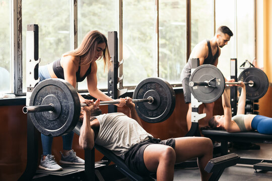 People training bench press in the gym with spotters