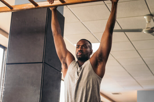 Black man doing pull-ups in the gym in front of the mirror
