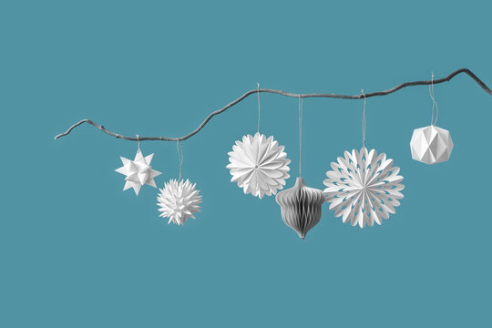 Paper Christmas ornaments on silver branch.