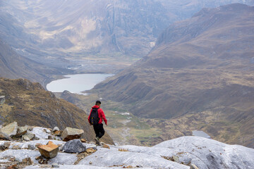 Hombre con mochila Caminado por una monta&ntilde;a de rocas cerca a una laguna en Per&uacute; Sudam&eacute;rica 