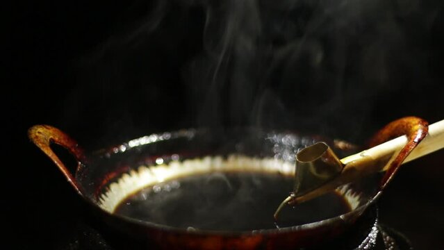 close-up videos. a pot that is concave and round over the fire. used as a melting wax / batik dye. Indonesian arts and crafts.