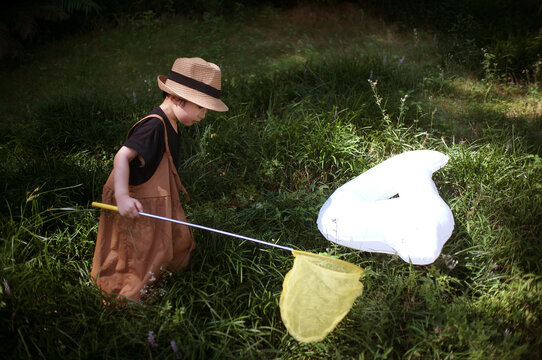 Cute little asian boy catching light and shadow on the grass