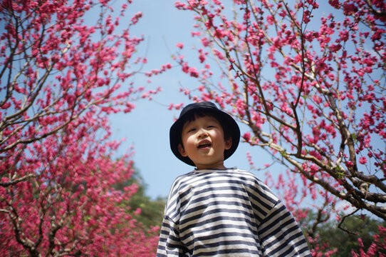 Cute little Asian boy playing under the peach tree