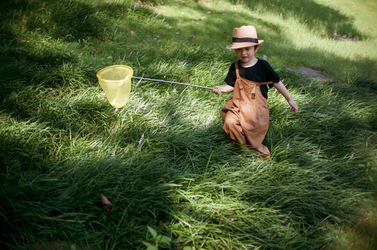 Cute little asian boy catching light and shadow on the grass
