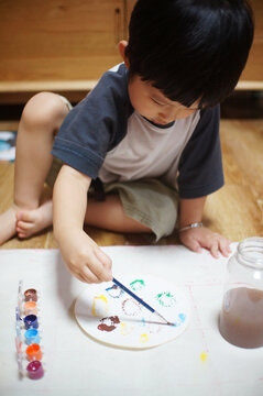 Cute little Asian boy drawing at home