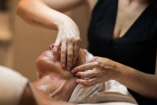 masseur massaging pleased client lying on massage table 